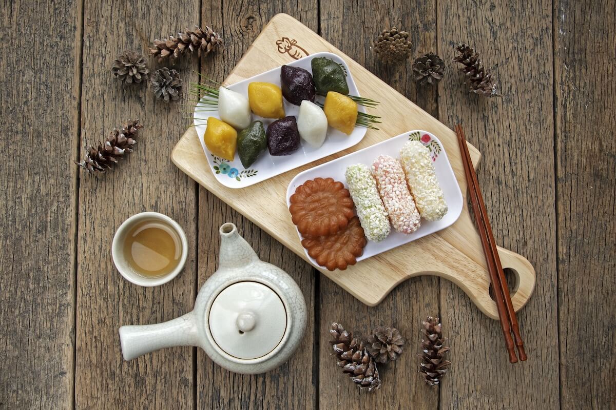Shutterstock: Top angle view of Songpyeon(half-moon-shaped rice cake) and Fried Rice Sweet with Yakgwa(Honey Cookie) and green tea on cutting board and wood floor, South Korea