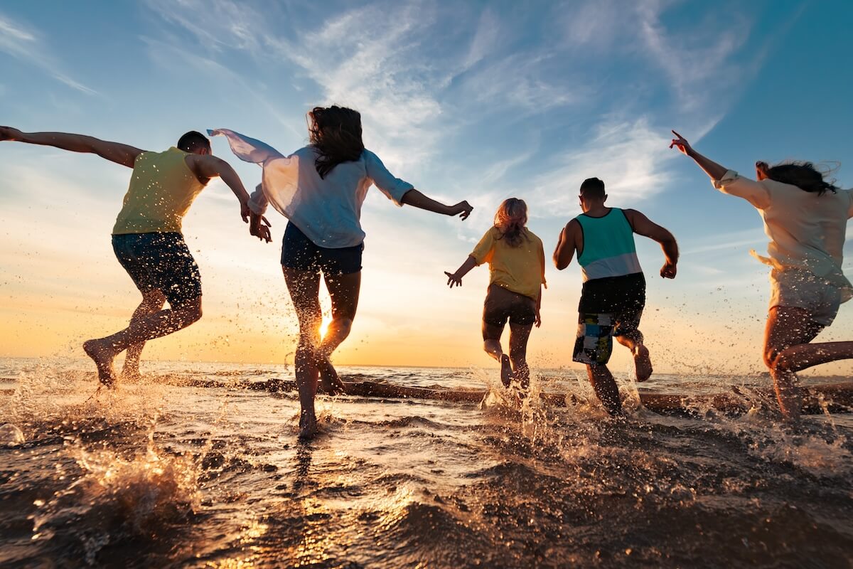 Shutterstock: Group of happy young friends are having fun, runs and jumps at sunset beach with lots of splashes
