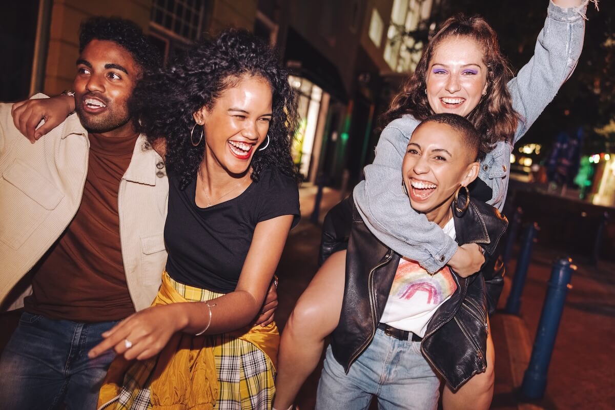Shutterstock: Young people laughing and living their best lives in the city. Happy young people having fun while hanging out together at night. Vibrant friends spending their weekend together.