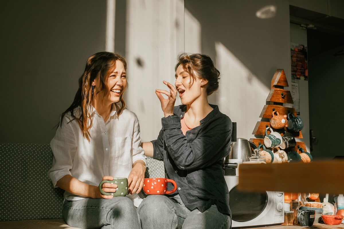 Shutterstock: Cozy morning: girls friends talking over a cup of coffee in a bright kitchen Two women spend time peacefully on a sunny day with mugs of tea