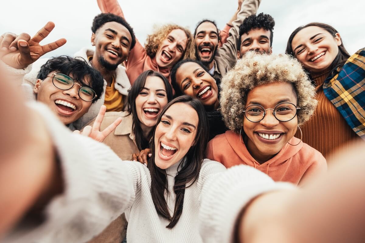Shutterstock: Big group of friends taking selfie picture smiling at camera - Laughing young people celebrating standing outside and having fun - Portrait photography of teens guys and girls enjoying vacation