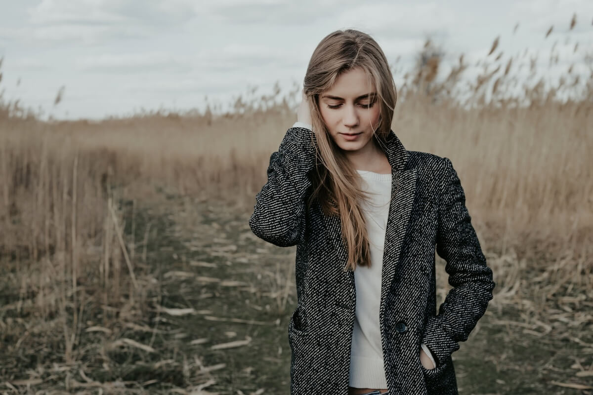 Shutterstock: Woman with long blond hair, wide eyebrows and with flying hair covered her cute face standing on country road and looking down . Girl adjusting her hair. Outdoor. Medium shot.