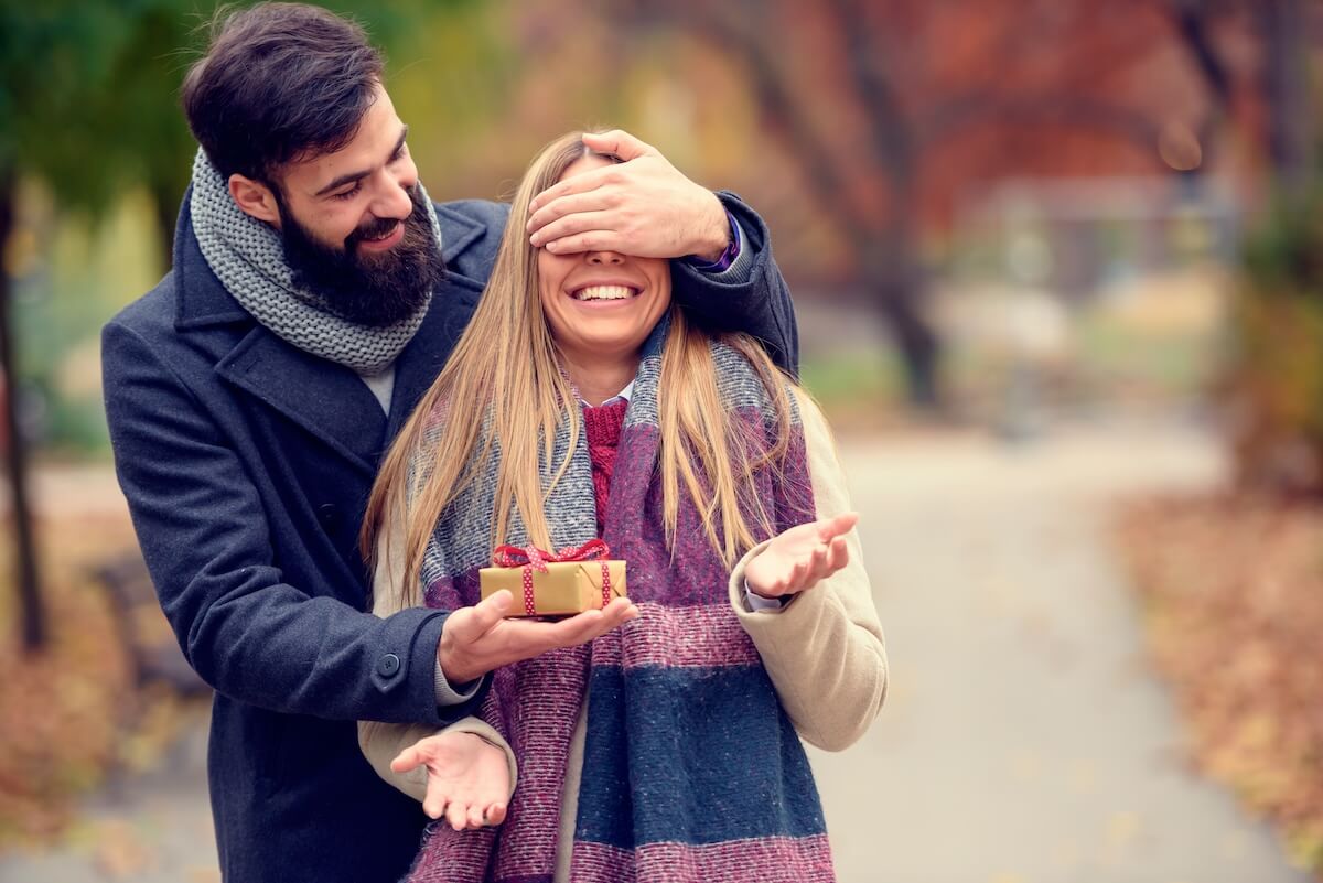 Shutterstock: Young hipster man wants to surprise girlfriend with a gift for Valentines Day covering her eyes