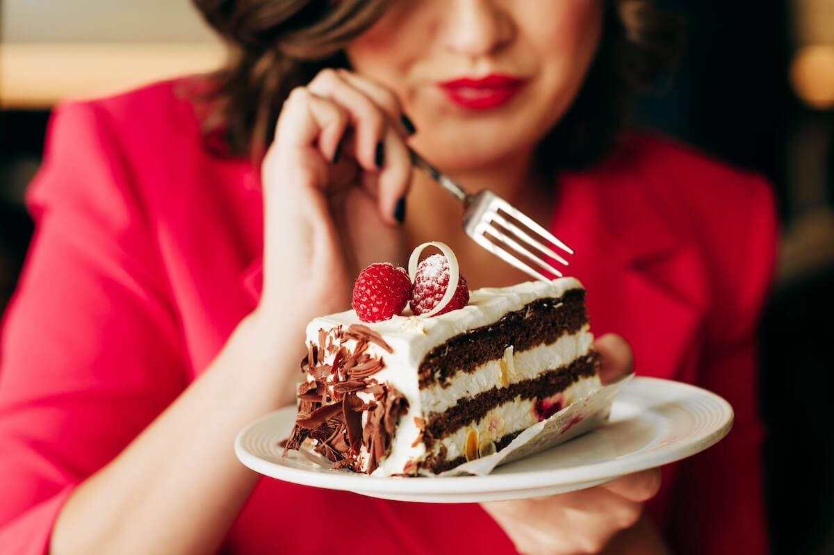 Shutterstock: Close up image of woman eating cake Black Forest decorated with white chocolate and raspeberries