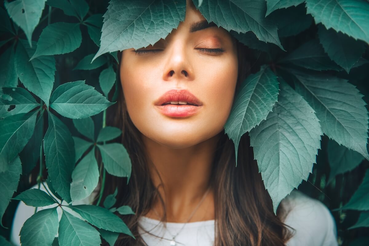 Shutterstock: Beautiful fashion model girl enjoying nature, breathing fresh air in summer garden over Green leaves background. Harmony concept. Healthy beauty woman outdoor portrait. Zen.