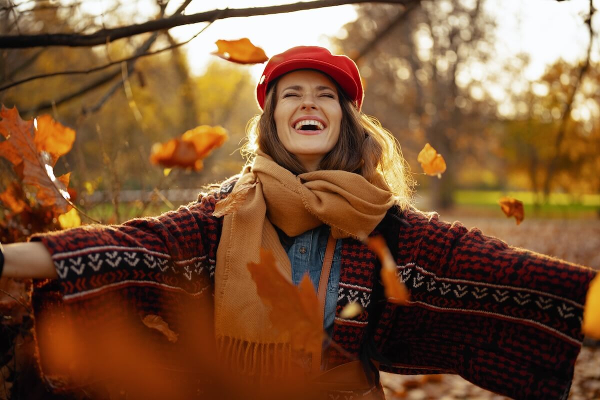 Shutterstock: Hello autumn. happy modern woman in red hat with scarf rejoicing in the city park.