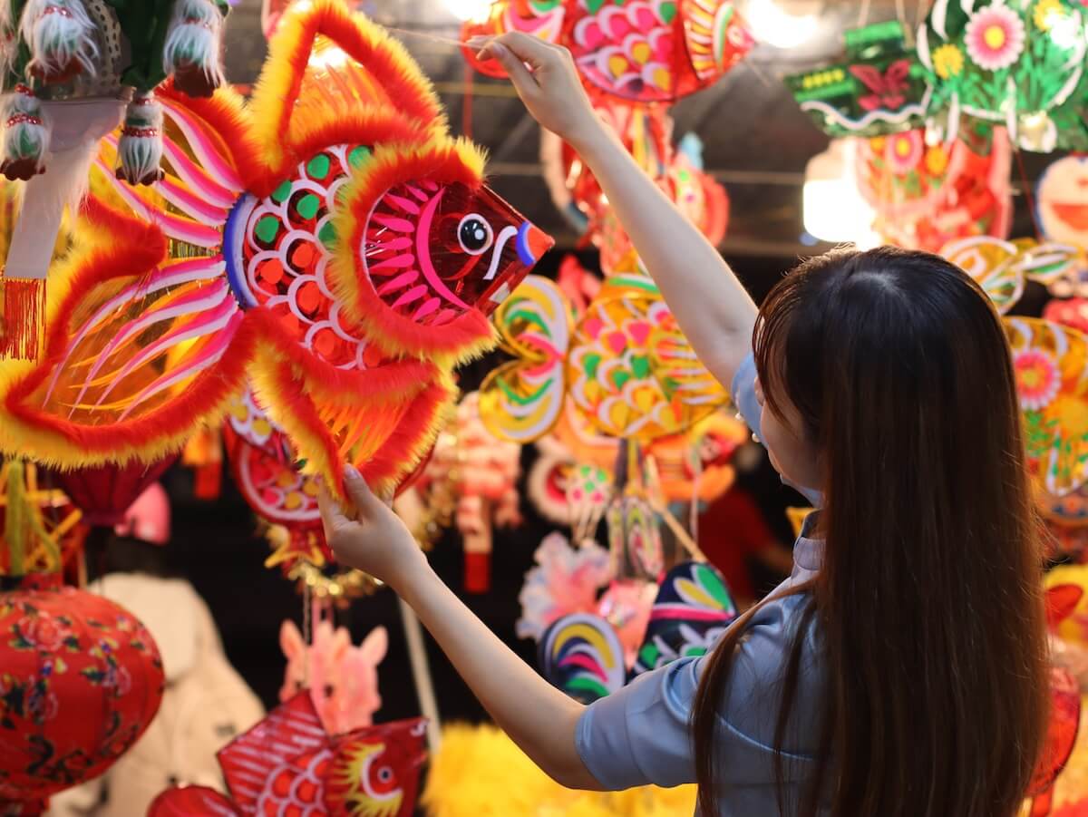 Shutterstock: A young girl in traditional attire joyfully celebrates the Mid-Autumn Festival. She is holding a colorful paper lantern, which is a classic symbol of the festival.
