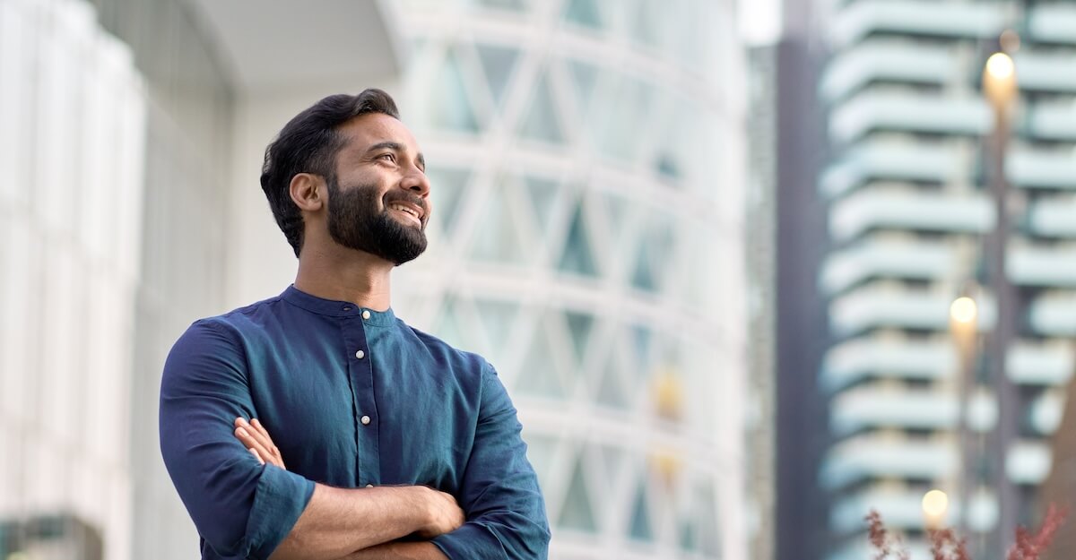 Shutterstock: Happy wealthy rich successful indian business man standing in big city modern skyscrapers street on sunset thinking of successful future vision, dreaming of new investment opportunities concept.