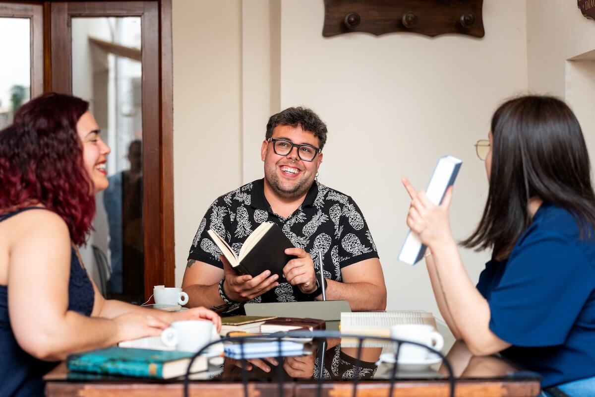 Shutterstock: Smiling friends enjoying a book club meeting at a cafe, discussing literature and sharing their thoughts