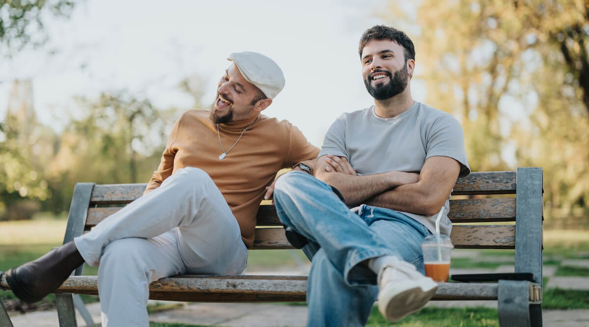 Shutterstock: Two guy friends meeting on bench for coffee in fall
