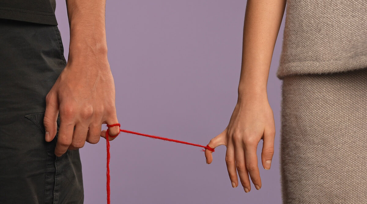 Shutterstock: Man and woman tied by pinkie finger by red string
