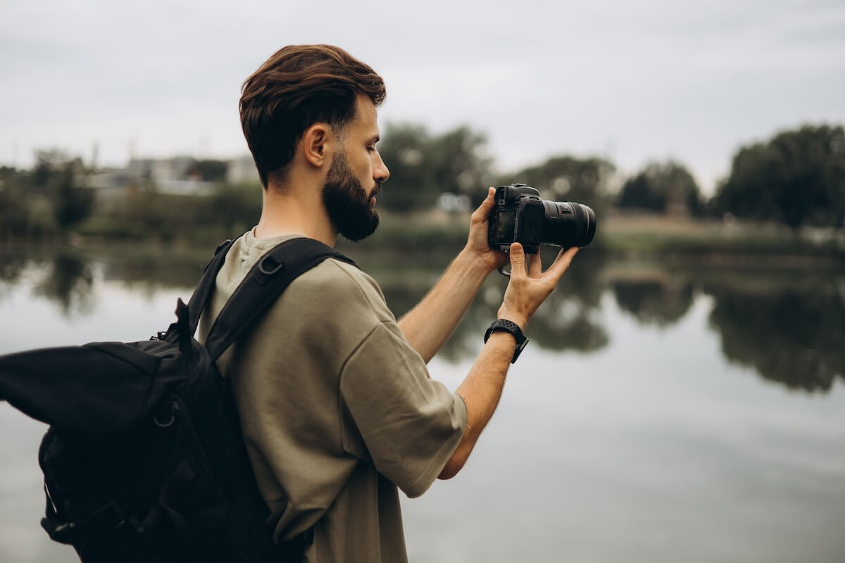 Shutterstock: a young man with a modern SLR camera in his hands on a natural background