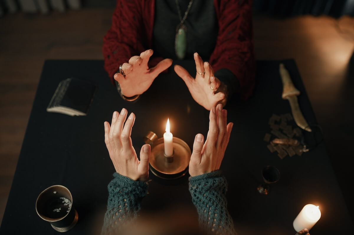 Shutterstock: Clairvoyant and client holding hand over candle flame top view