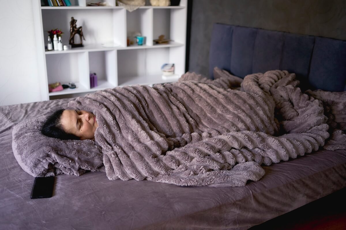 Shutterstock: woman sleeping under a weighted blanket