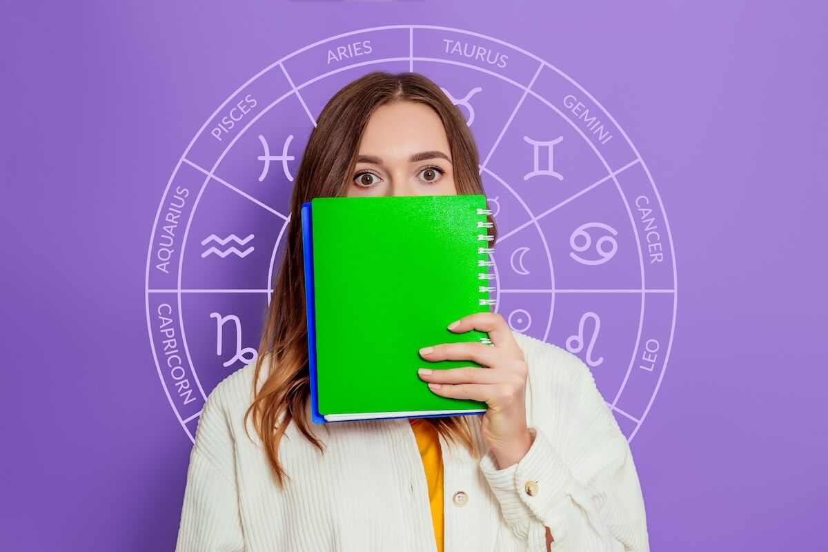 Shutterstock: Shocked young woman holding white poster in her hands with zodiac astrological circle isolated on lilac background