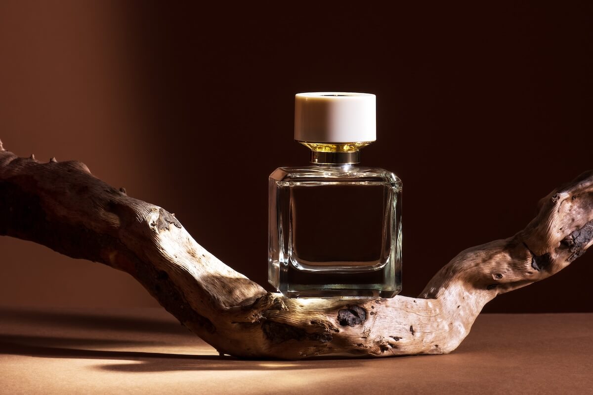 Shutterstock: Transparent perfume bottle with aged weathered wooden branch on brown background.