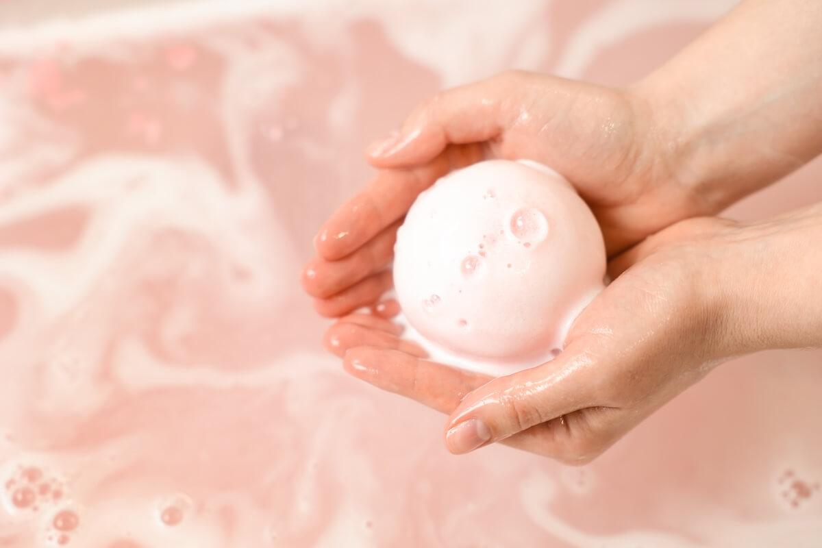 Shutterstock: Woman with bath bomb above water, closeup