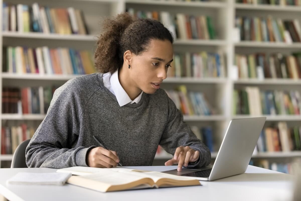 Shutterstock: Focused Hispanic student guy sit at desk in library, studying using laptop, e-learns, improve subject knowledge, preparing to enter higher education institution using application. Gen Z and education