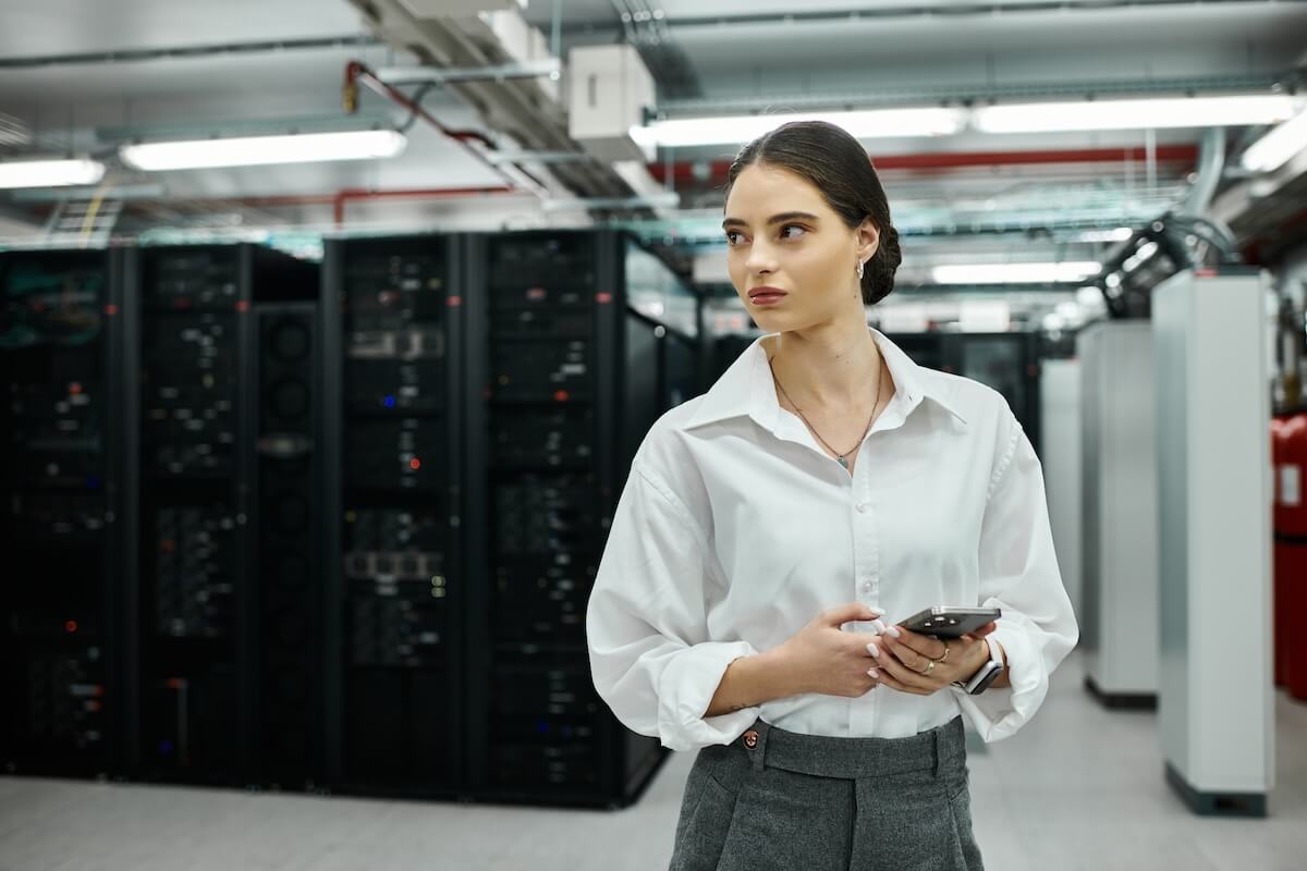 Shutterstock: Dedicated IT specialist in a white shirt monitors server status in a high-tech environment.