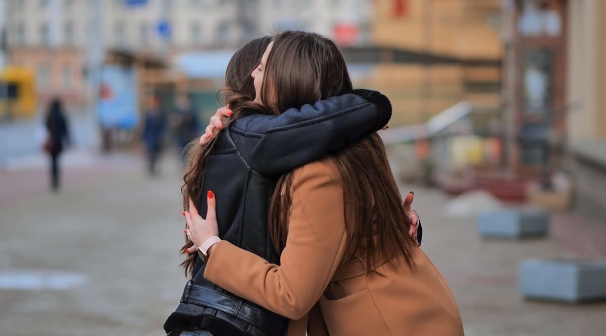 Shutterstock: Two best friends meet on the streets of the city and hug.