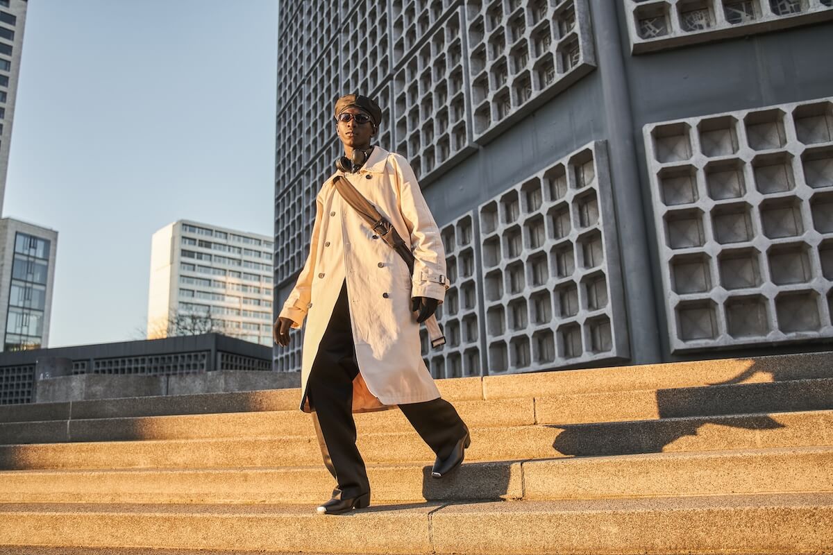 Shutterstock: Full length view of multiracial man in casual style trench coat standing at street stairs