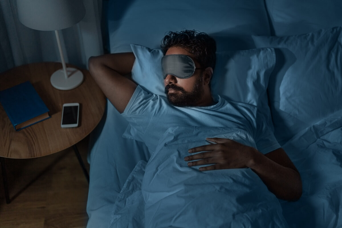 Shutterstock: people, bedtime and rest concept - indian man in eye mask sleeping in bed at home at night