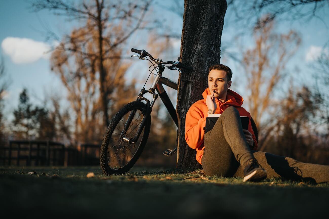 Shutterstock: Man thoughtfully writing under tree
