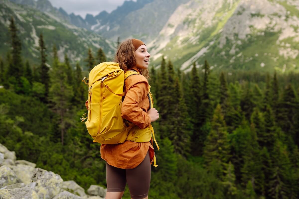 Shutterstock: Woman packing through a forested mountain trail