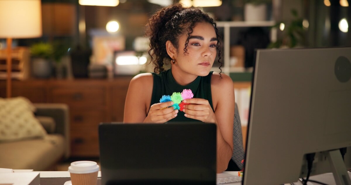 Shutterstock: Business woman, laptop and thinking with popit, creative agency and project ideas for night calming. Girl, brand consultant and multi screen computer with ADHD, soothing and fidget stimming in office