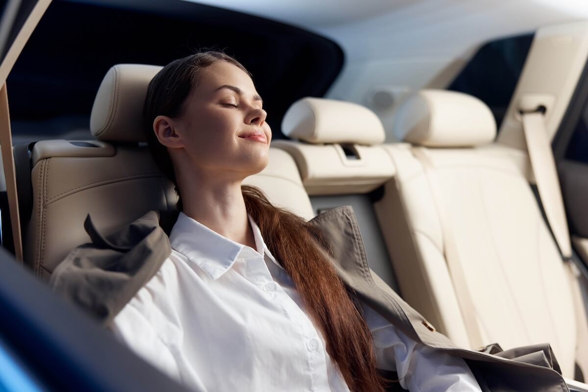 Shutterstock: Sleeping woman in car a woman peacefully sleeps with her eyes closed and head resting on the back seat of a moving vehicle, capturing a moment of tranquility and relaxation during travel