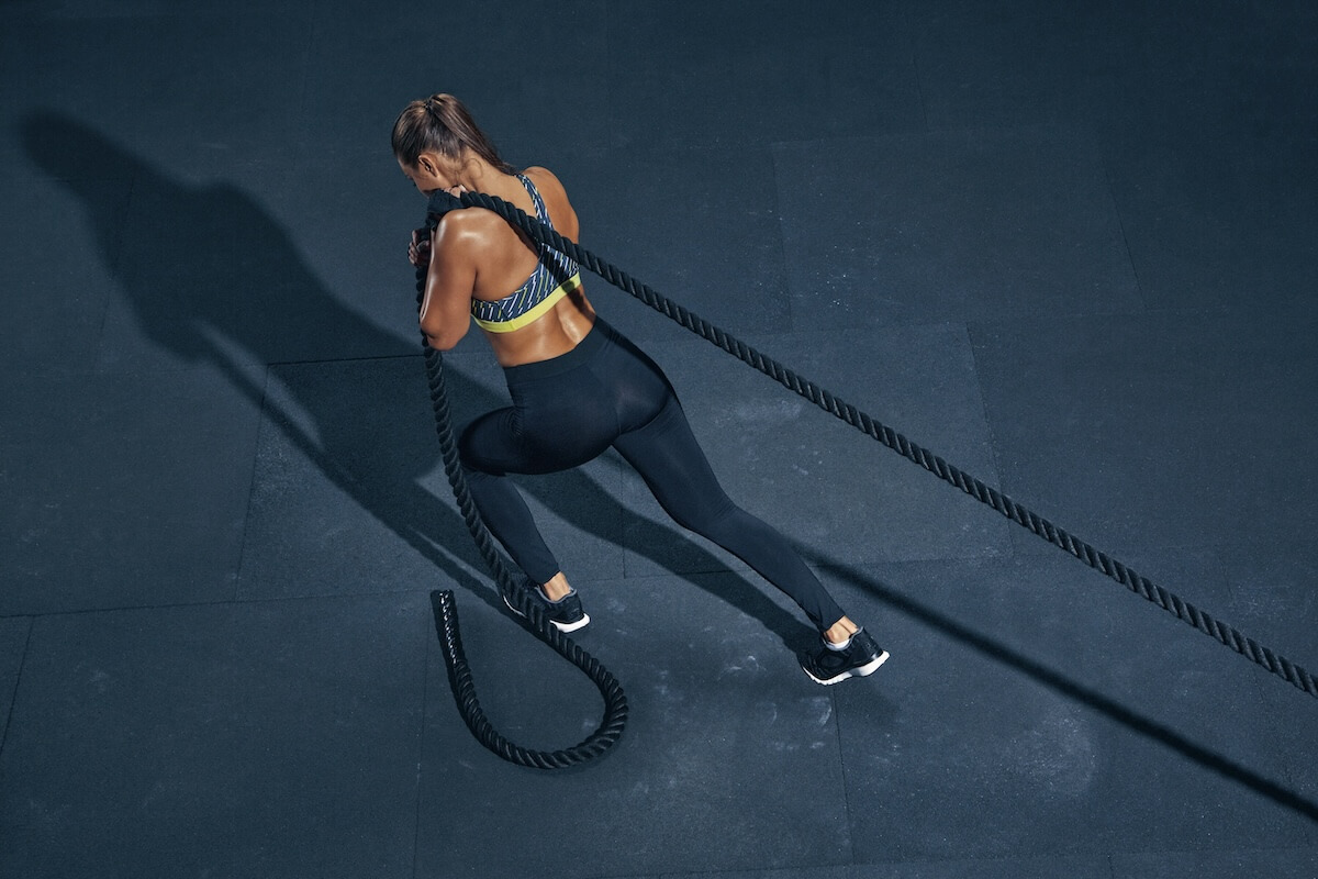 Shutterstock: Female athlete fitness rope pull training. Sporty sportswoman working out in functional training gym doing cross exercise with battle rope.